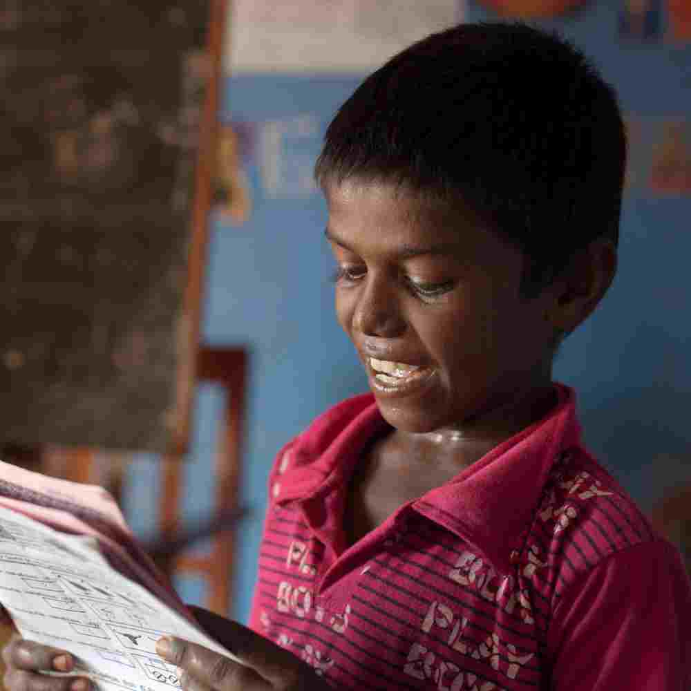 Young boy reading in GFA World child sponsorship Bridge of Hope center