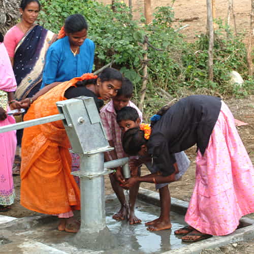 Women and children enjoy clean water from a Jesus Well drilled by GFA World