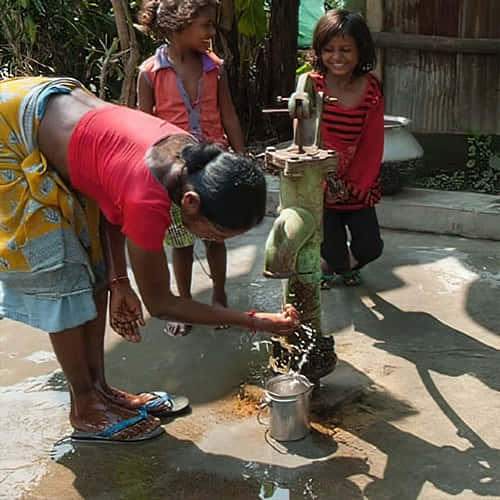 A mother and her children draw clean water through GFA World Jesus Wells
