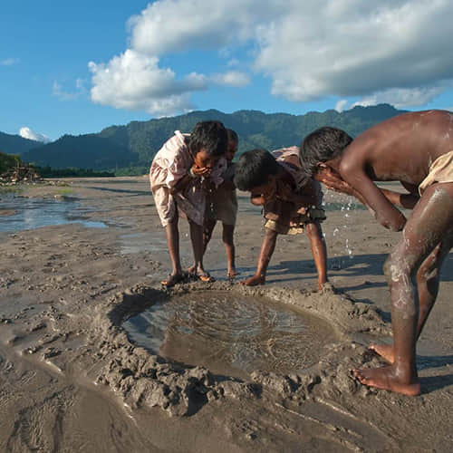 Young children forced to drink water from an open water source due to water scarcity