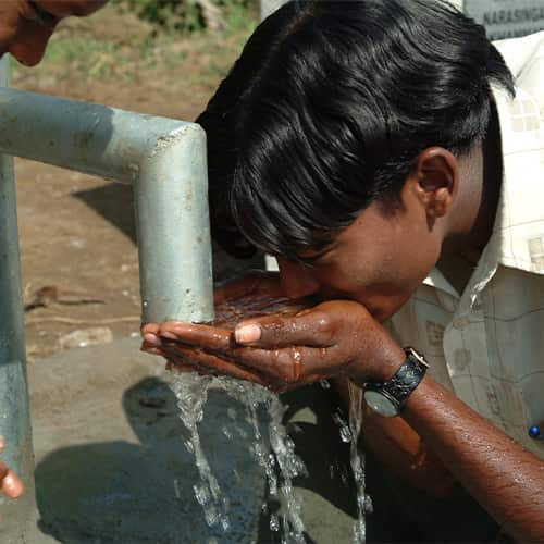 Young boy drinking clean water through GFA World Jesus Wells