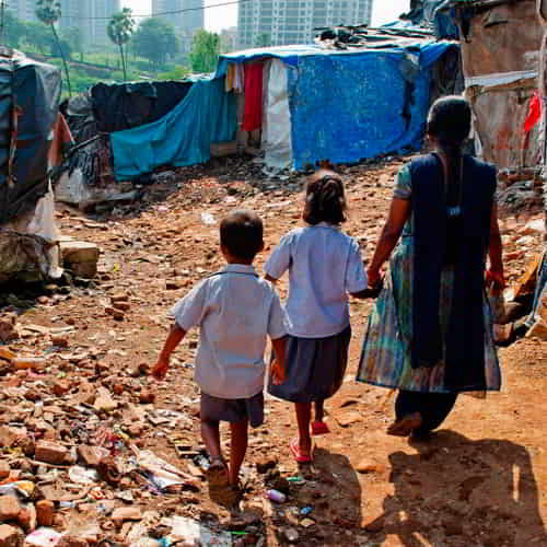 Mother and her children walking to their home in a slum in South Asia