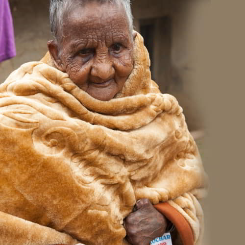 An elderly leprosy patient received a warm blanket through GFA World gift distribution