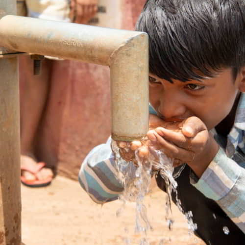 Young boy drinking clean water through GFA World Jesus Wells water solutions