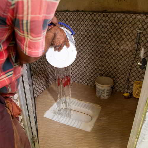 Washing GFA World outdoor toilet with clean water from Jesus Wells