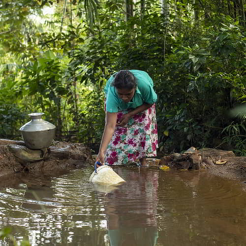 Woman collecting water from contaminated water source