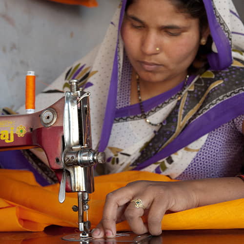 A woman learning to use a sewing machine through GFA World tailoring class