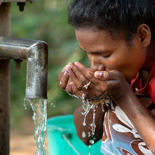 Woman drinks clean water through GFA World Jesus Wells