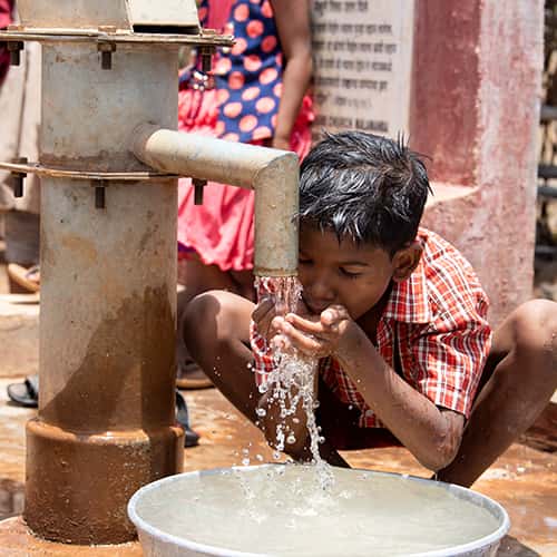 Young boy drinks clean water through GFA World charity Jesus Well
