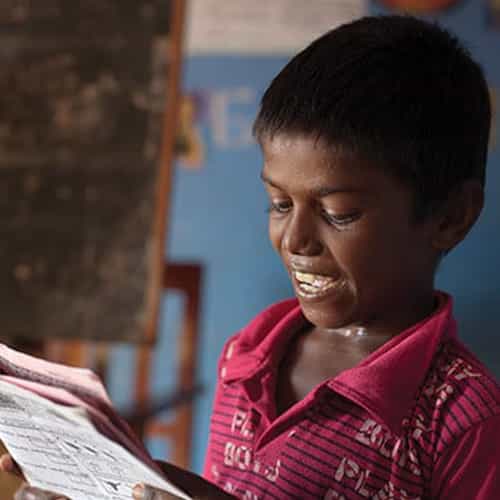 Young boy reads workbook in GFA World child sponsorship program