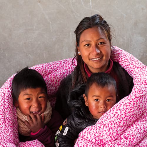 Rosina and her children enjoy a warm blanket through GFA World gift distribution