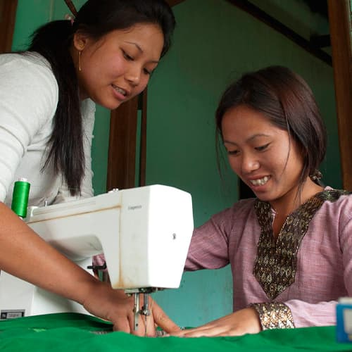 Women learn how to use a sewing machine through GFA World tailoring class
