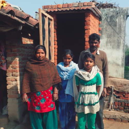 Girls and their family outside a GFA World provided outdoor toilet
