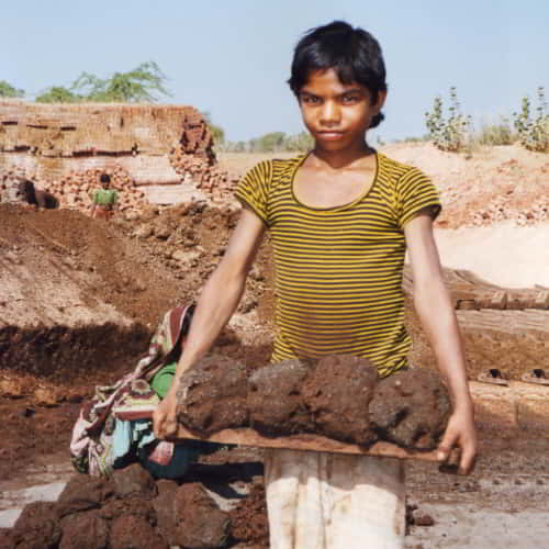 Young boy in child labor due to poverty in a brick kiln in South Asia