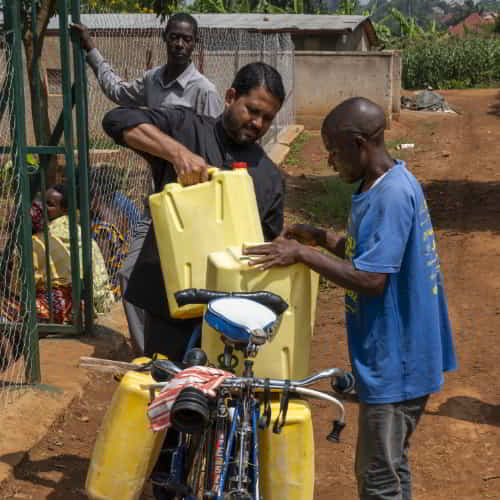 GFA World national missionary worker assisting African man to load clean water from Jesus Wells