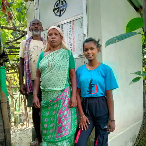 Young girl and her family outside a GFA World provided outdoor toilet